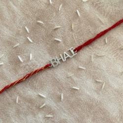 A Quirky Silver Bhai Text Rakhi With Traditional Red Thread For Brother